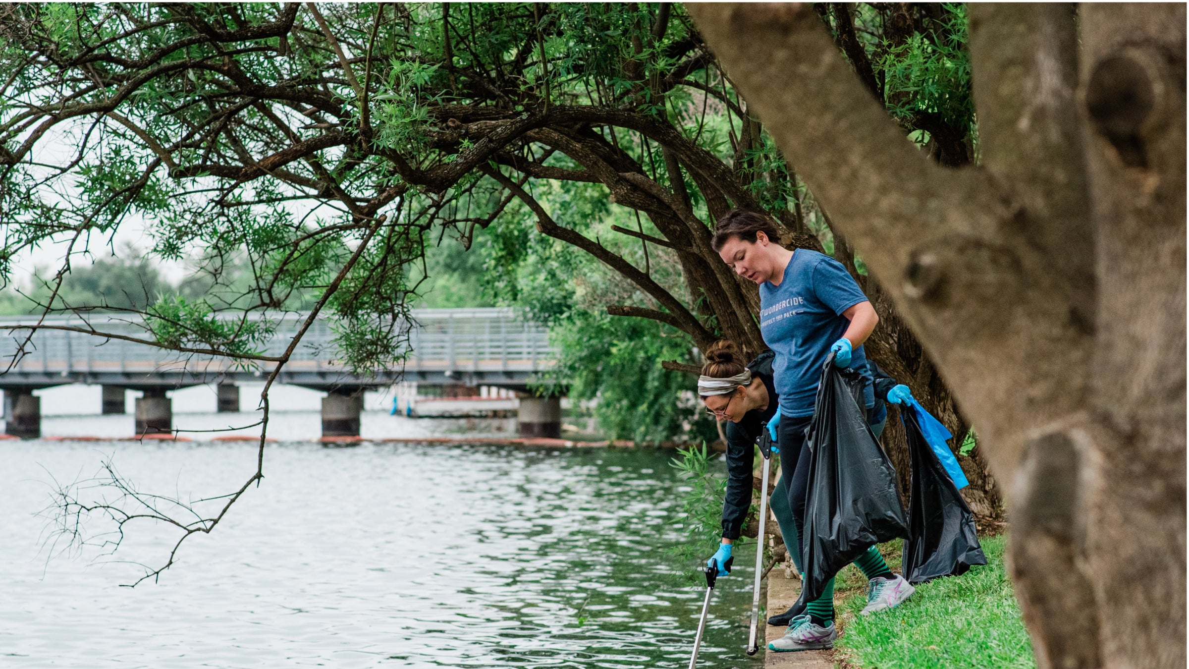 Two Wondercide employees pick up litter from the river edge in Austin Texas