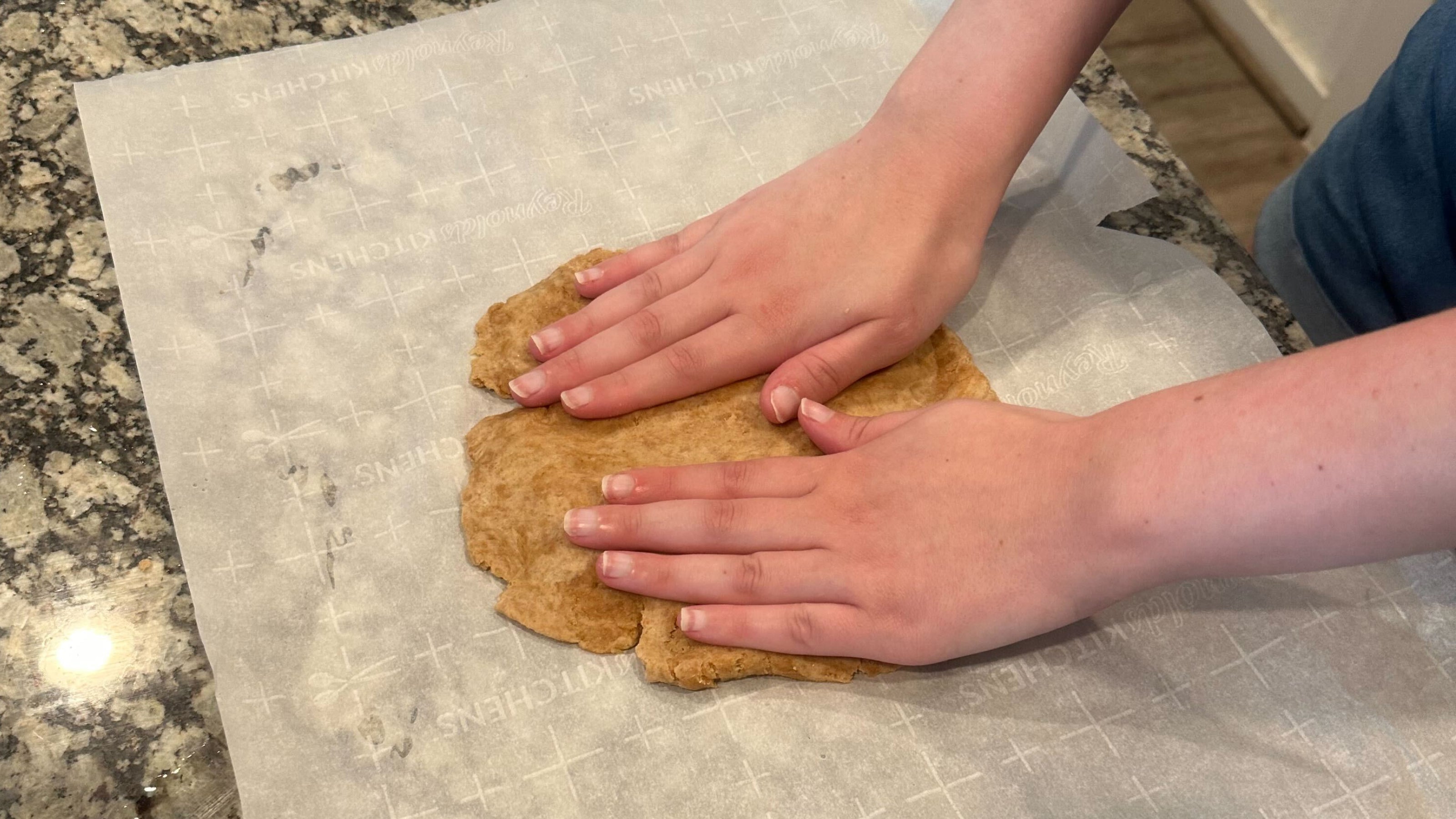 Two hands roll dog treat dough on parchment paper