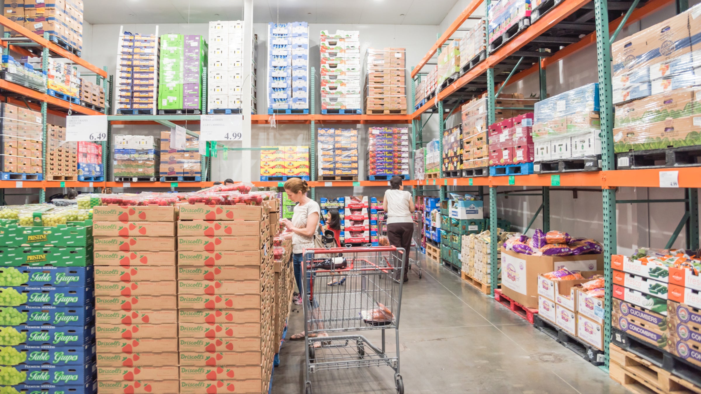 Two shoppers buying in bulk in the produce section of a club memership store