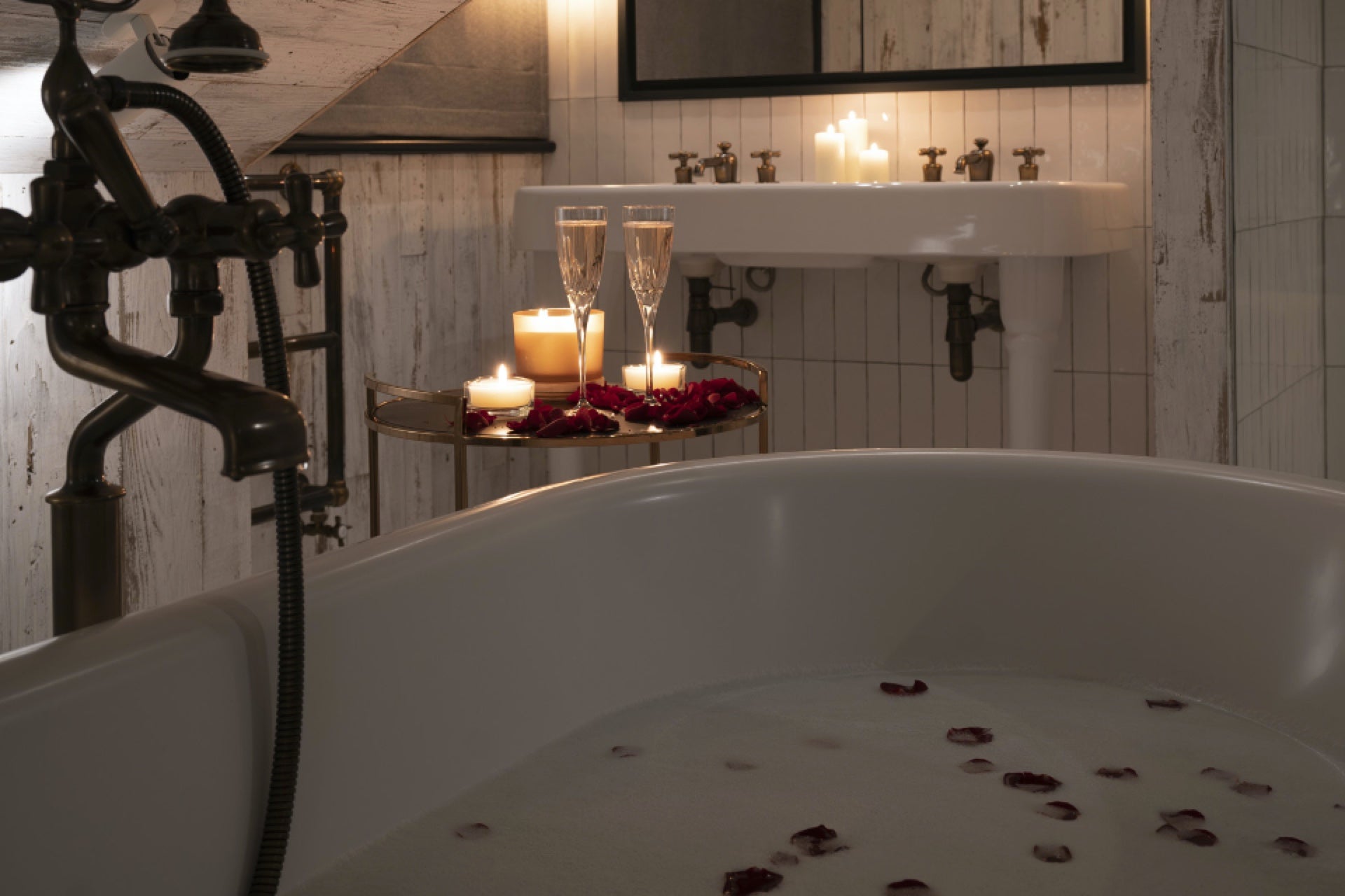 Candle lit bathroom with rose petal bubble bath and champagne