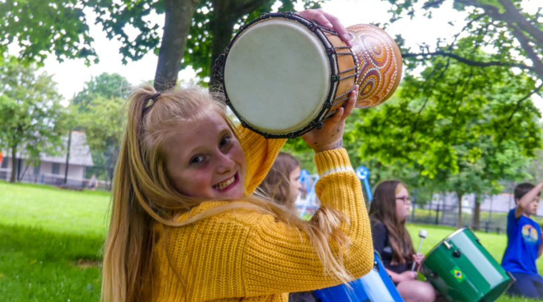 Omaze Million Pound House Kent Draw - Global's Make Some Noise Charity Girl in a yellow jumper holding a drum in the air 