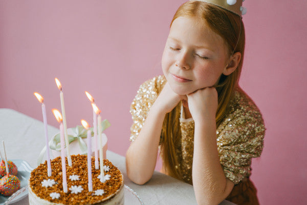 Une fillette fait un vœu devant son gâteau d'anniversaire