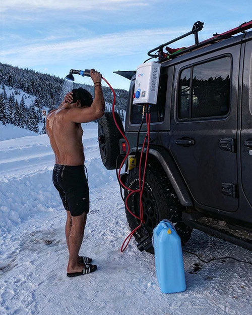 Man taking a hot shower on a snowy day with the HOTTAP portable shower