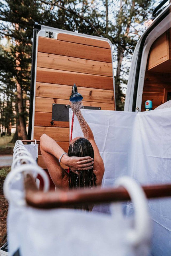 woman showers at the back of a camper