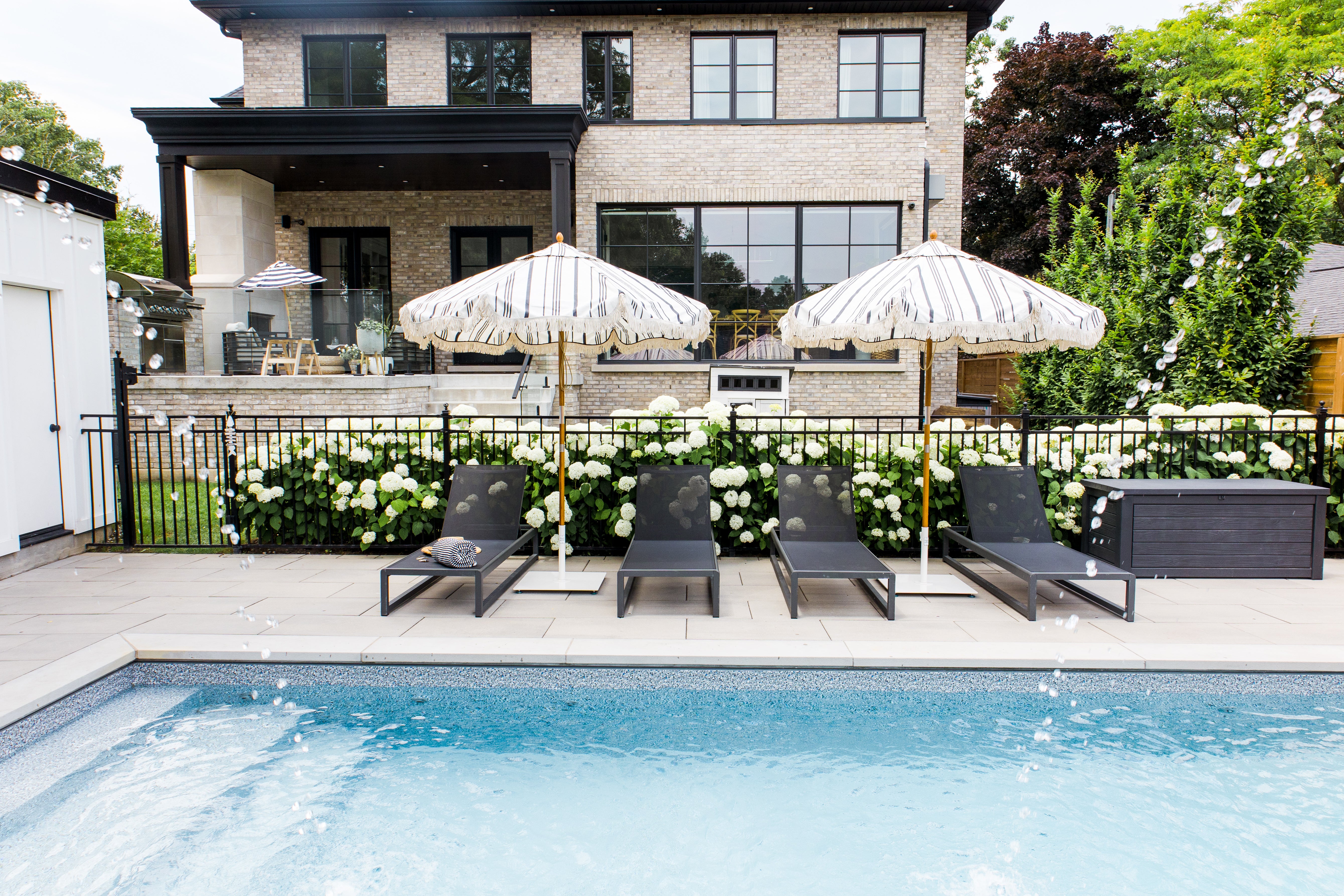 Pool with black loungers and striped umbrellas