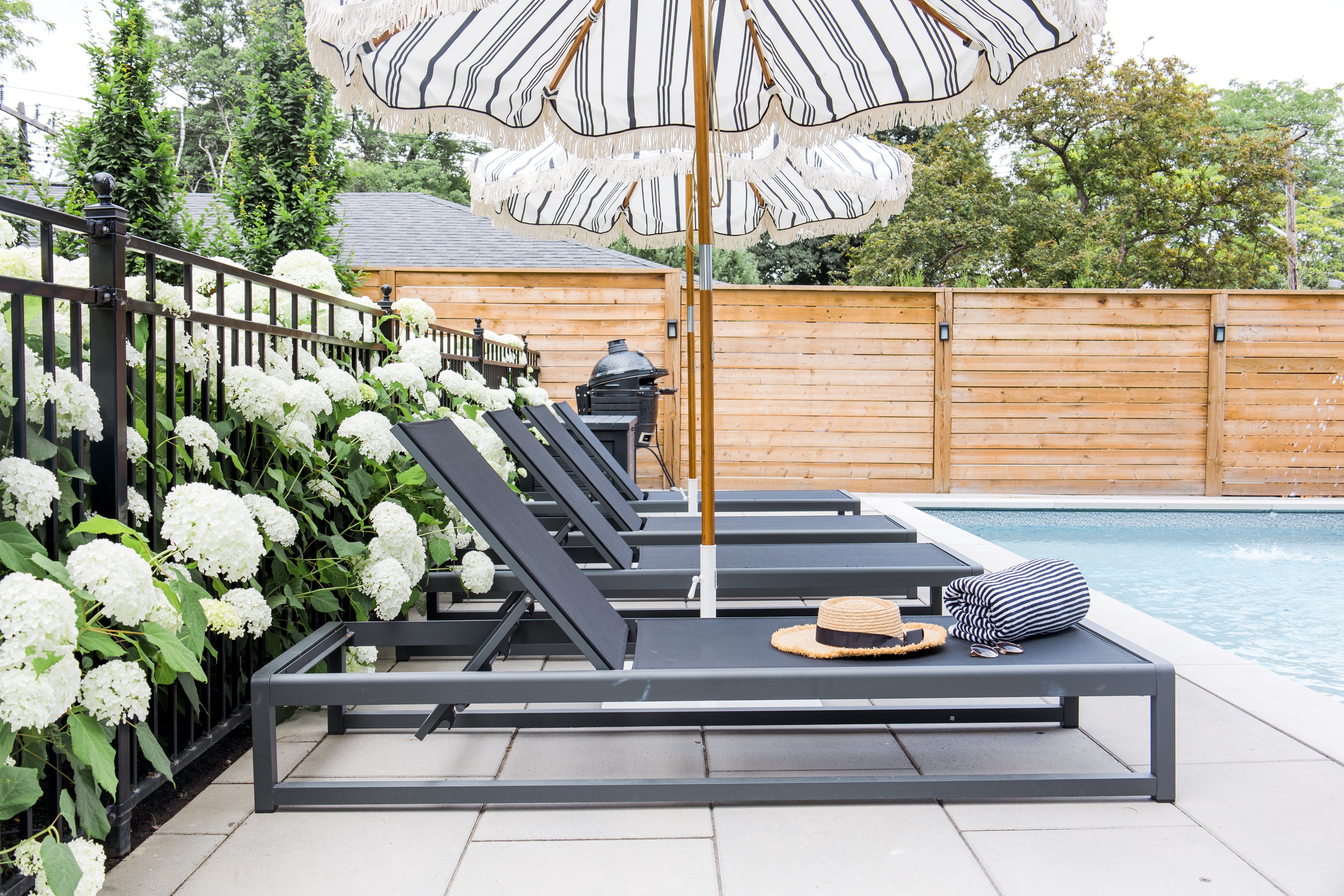 black pool loungers next to hydrangea lined fence