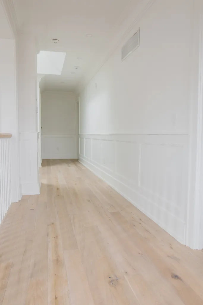 Empty hallway with white oak hardwood floors and white walls