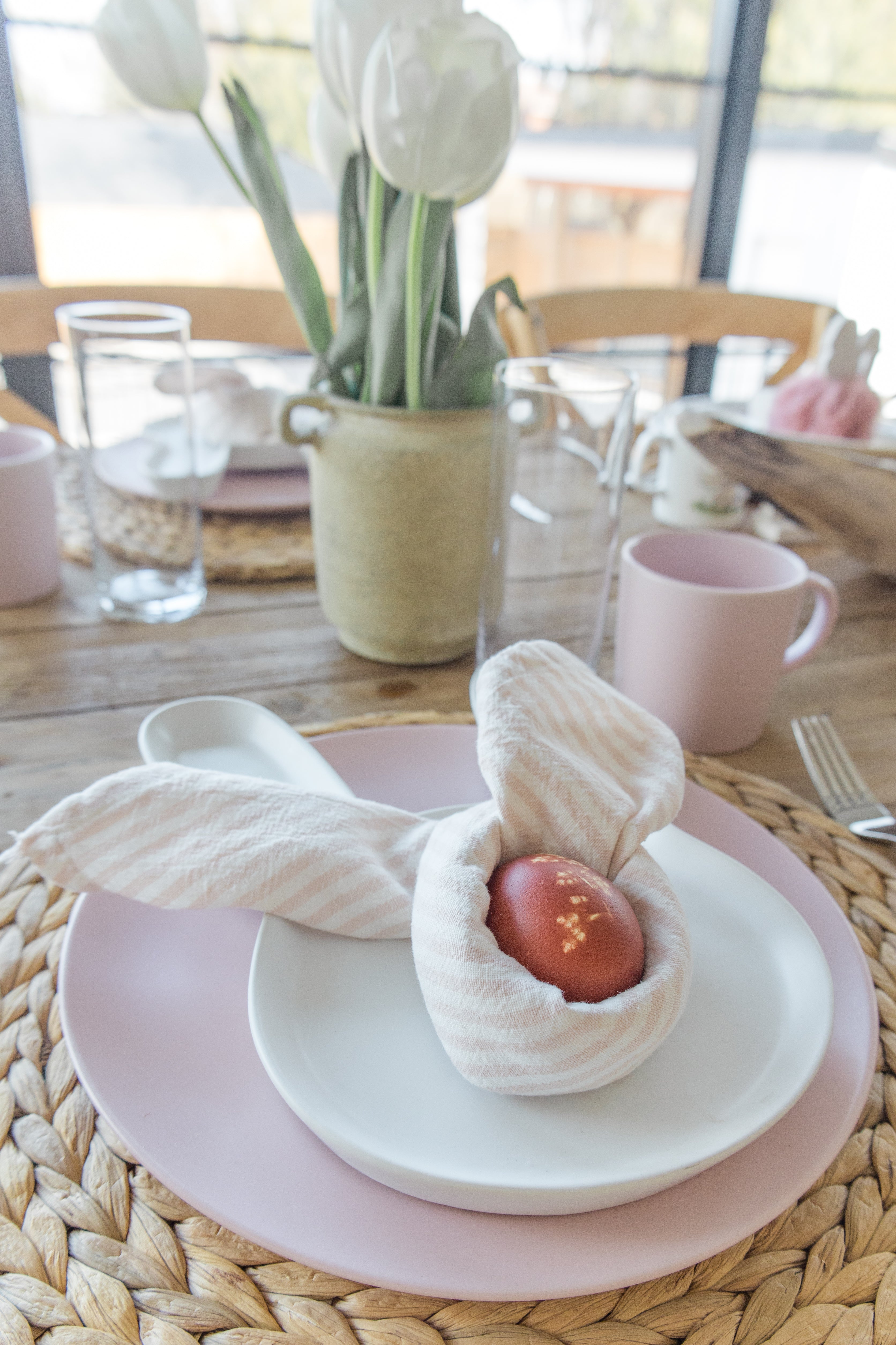Easter tablescape with napkin wrapped around egg sitting on a plate