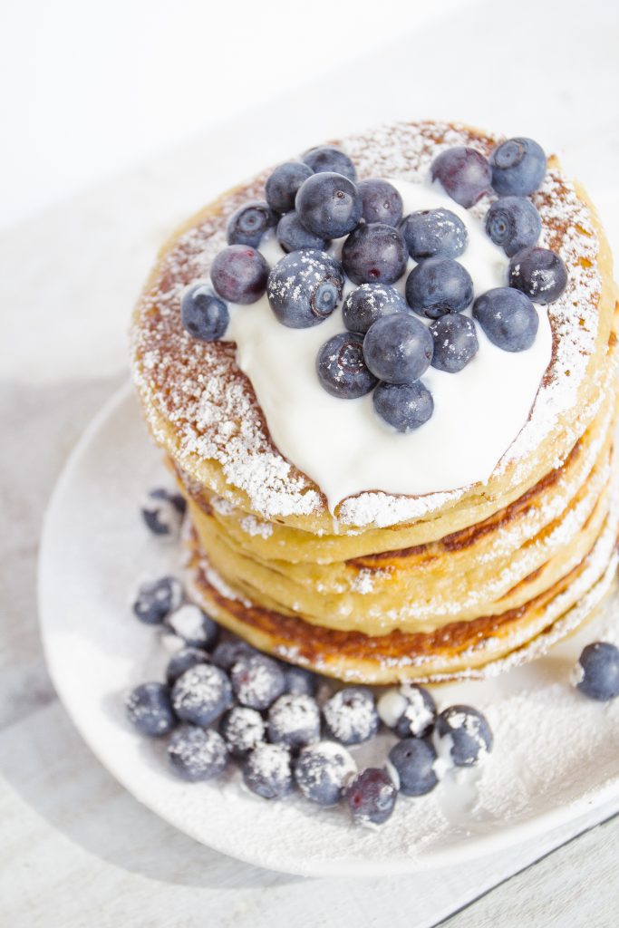 Stack of pancakes topped with Danone plain yogurt and blueberries