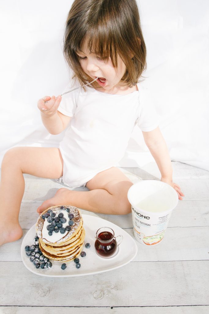 Toddler eating Danone yogurt and pancakes