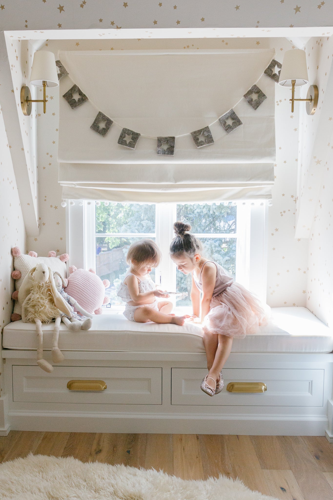 sisters sharing bench seat in big girl room