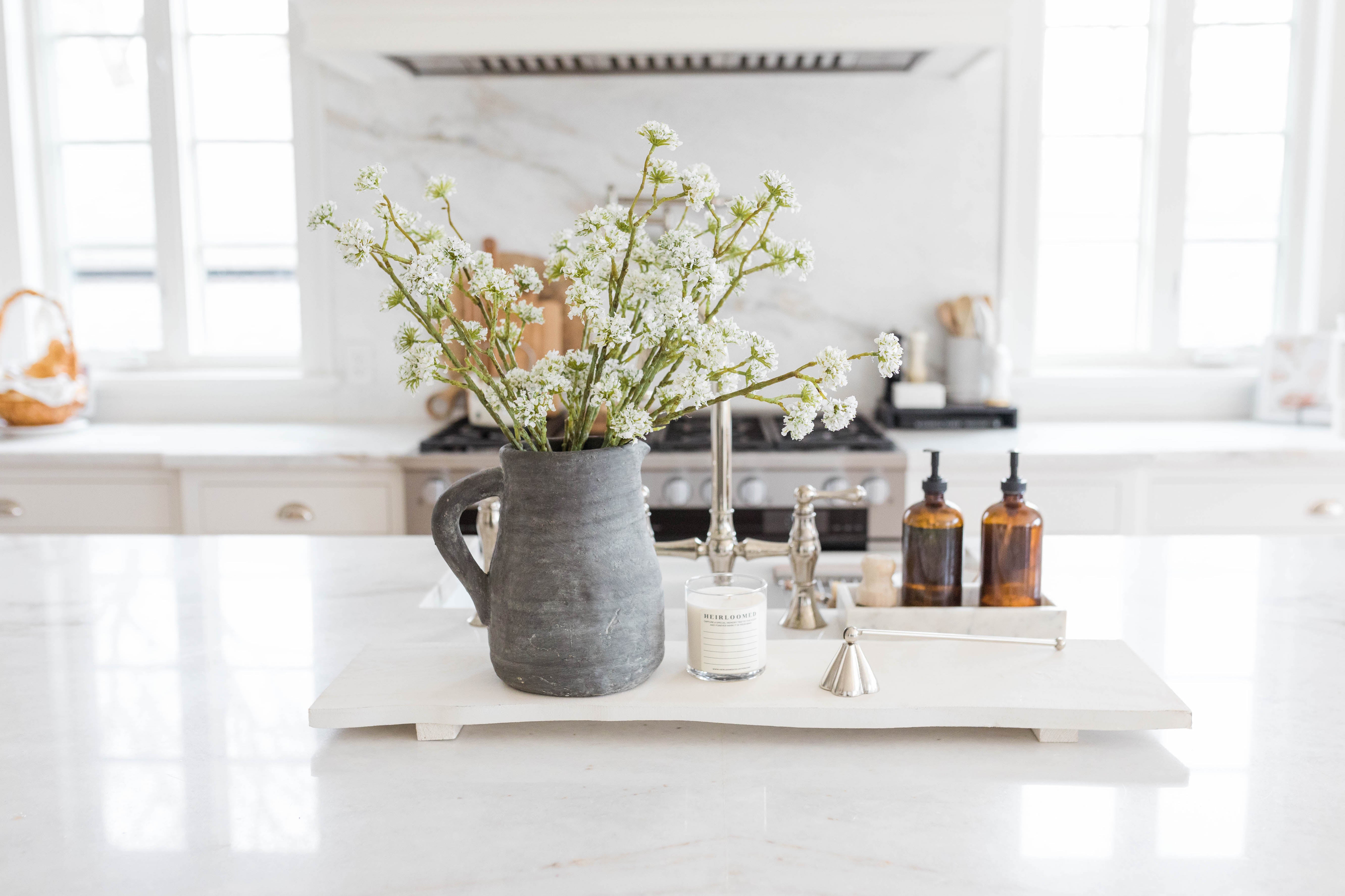 board styled with flowers and candle on  kitchen island 