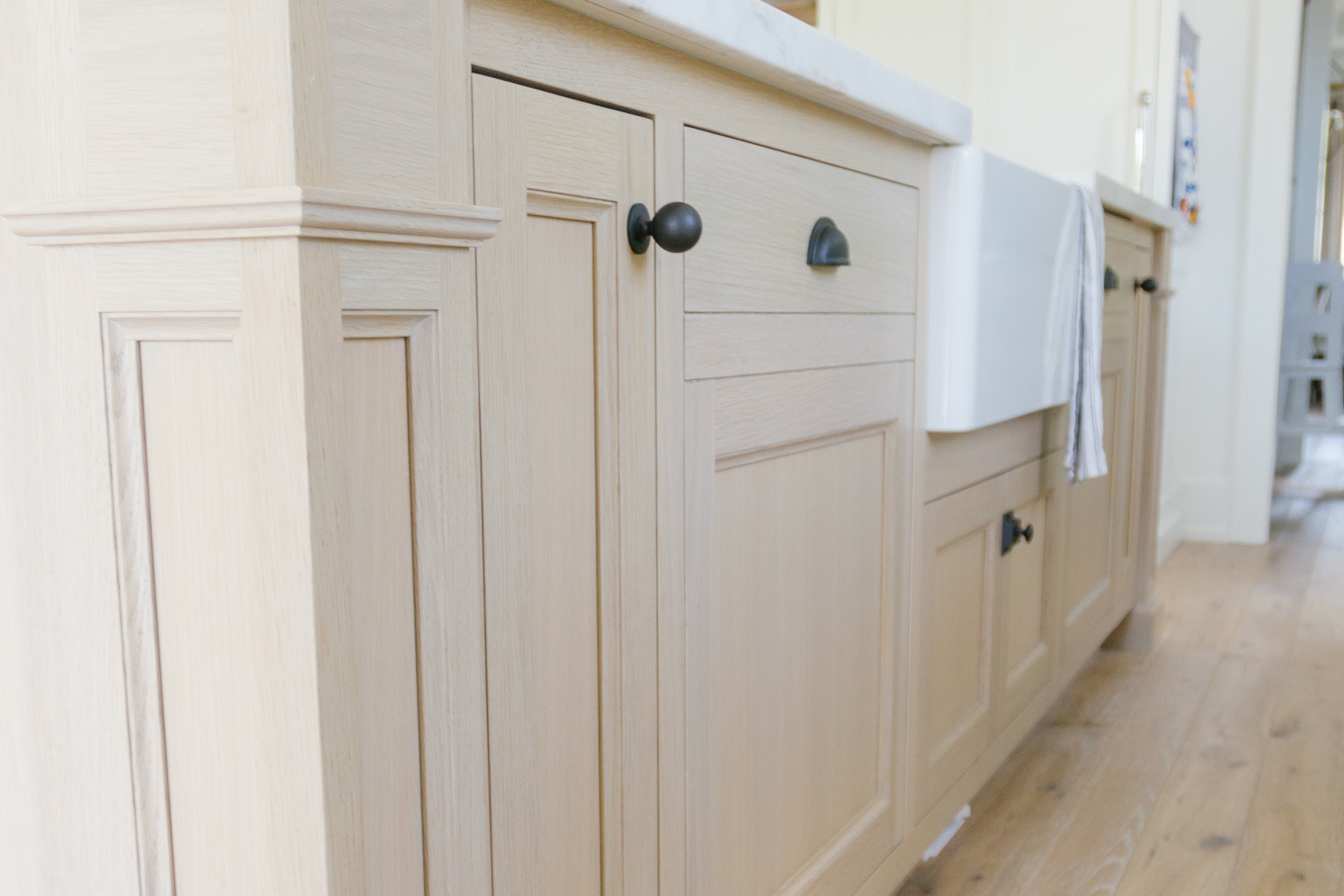 white oak kitchen cabinets with matte black hardware and farmhouse sink