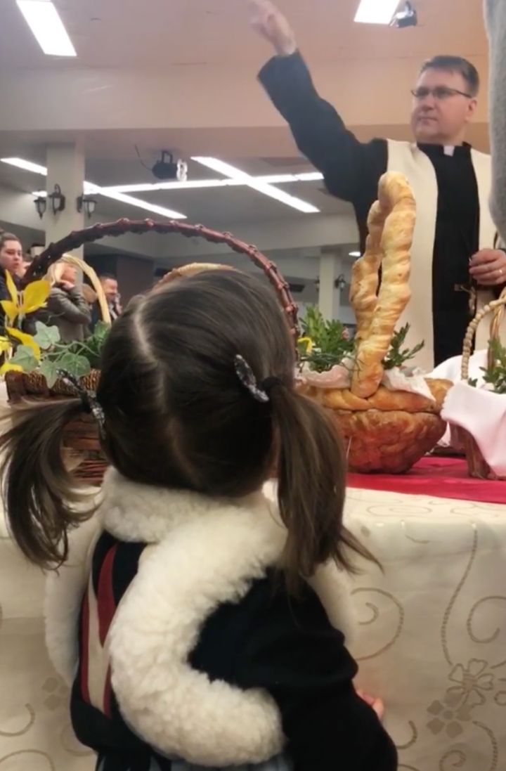 Daughter watching priest bless Easter basket TKL