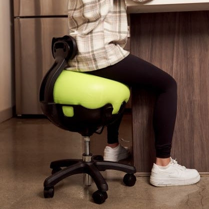 Woman sitting on a green exercise ball chair