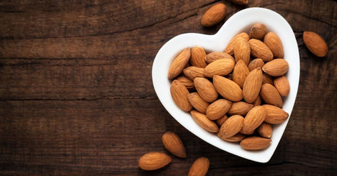 A heart shaped dish of raw almonds