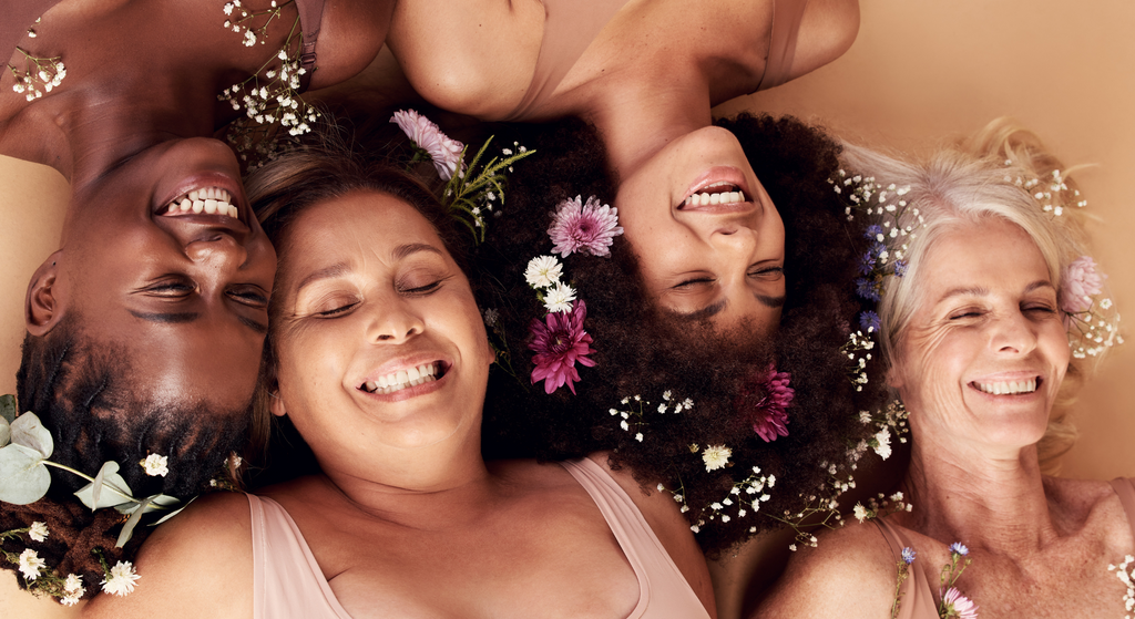 four women faces with flowers diverse fresh faced, clean beauty
