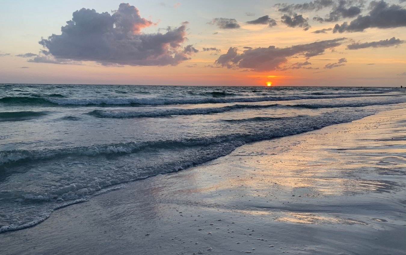 A serene sunset on the beach, small waves are slowing making their way to shore. The calm before the sh*t storm of 2020.