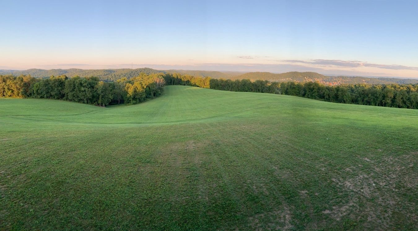 A beautiful green pasture on the rolling hills of southwestern Pennsylvania overlooking the forest. The view of the family farm.