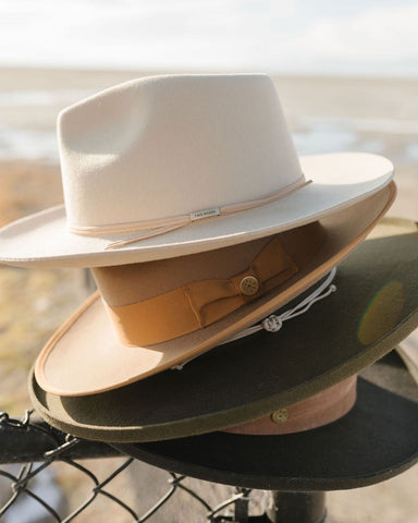 Four Two Roads men's hats for smaller heads stacked atop one another in white, brown, green, and black