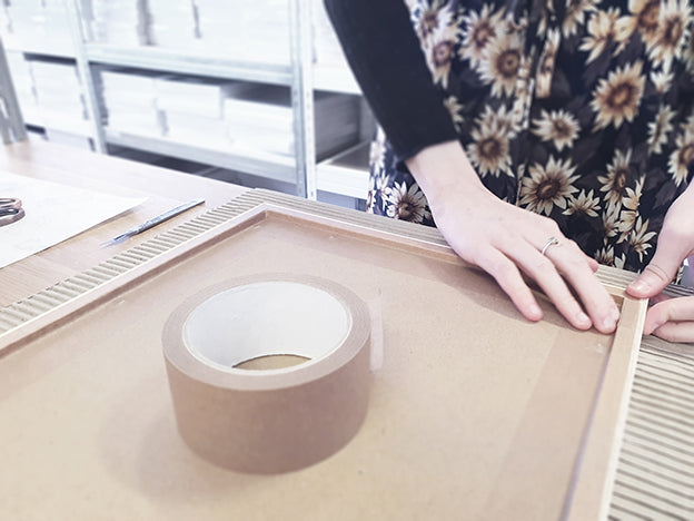 taping the back of a picture frame with archival gum tape