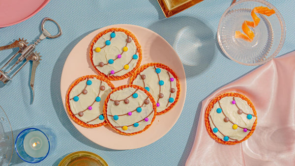 Stroopwafels decorated with frosting and m&ms to look like Christmas lights