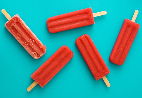 Strawberry popsicles over a bright blue backdrop