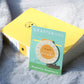 Shine Bright Sunshine Magnetic Bookmark by Craftedvan, in it's packaging and alongside a book.