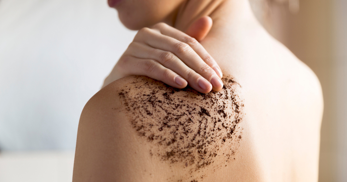 A woman using a body scrub on her shoulder to help with her skin tone and texture.