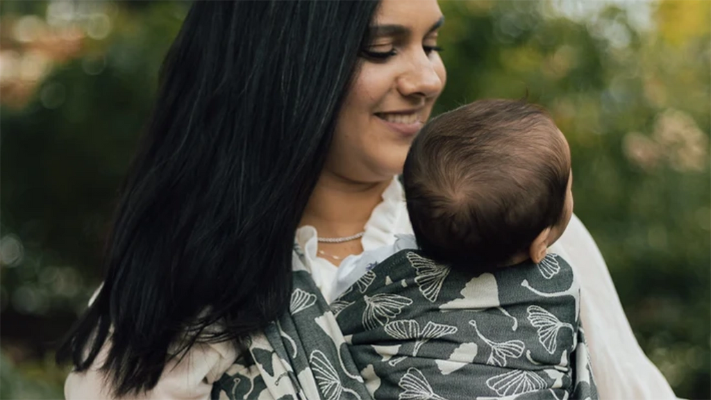 A mother carries her newborn in a woven baby wrap from Chimparoo.