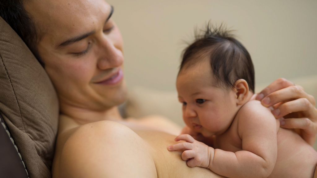 Un papa comblé avec son nouveau-né en peau à peau contre lui, une belle pratique pour renforcer le lien entre parent-enfant.