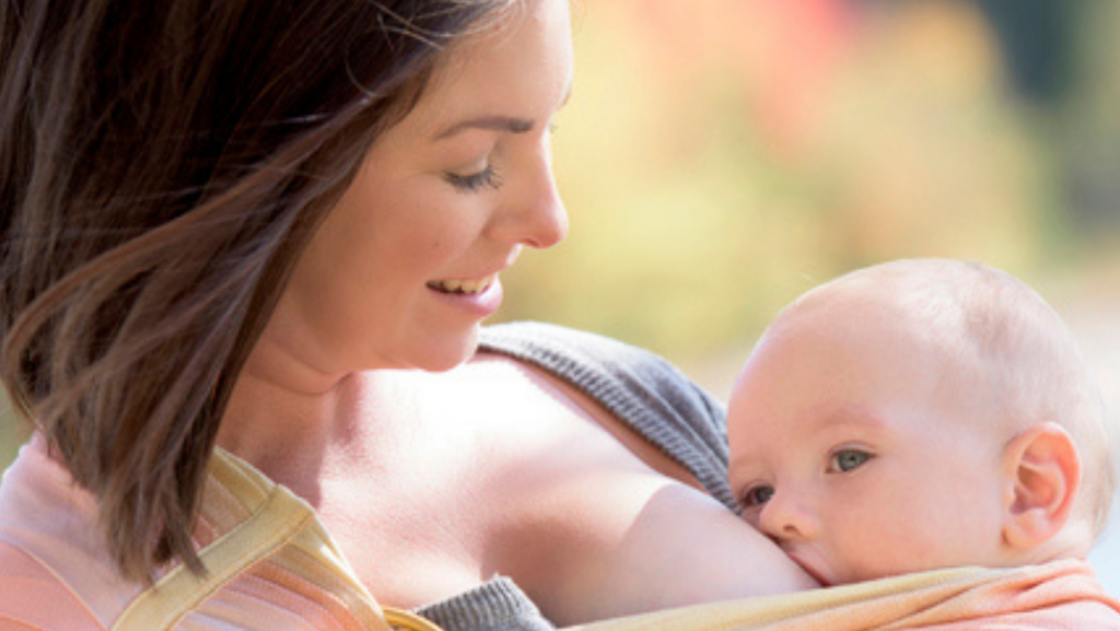 A mother breastfeeding her baby while carrying him in her ring sling.