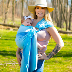 A mother taking a walk with a baby on her hip in a ring sling.