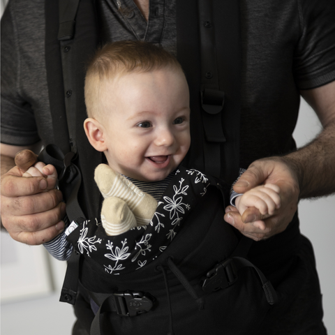 A baby in a PöpNGo baby carrier, worn by his dad!
