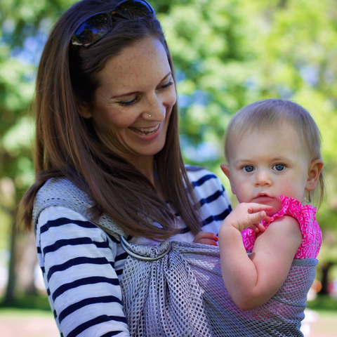 Une maman qui porte sa fille avec l'écharpe ajustable Ring Sling Chimparoo.