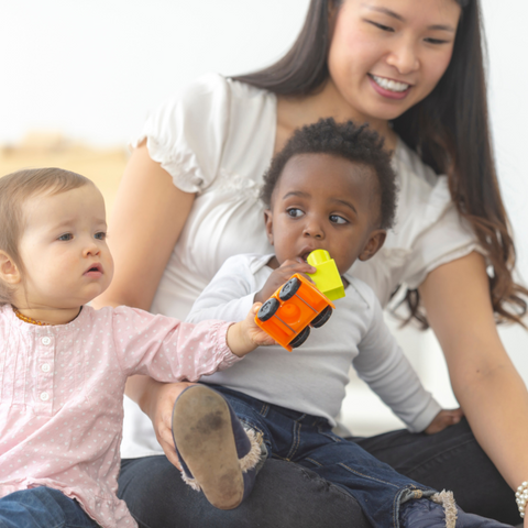 An educator at the daycare surrounded by children.