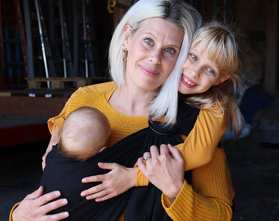 A mother with her two children carrying her infant with the Ring Sling