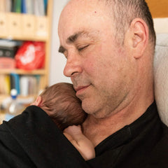 Un papa se repose avec son nouveau-né en peau à peau.