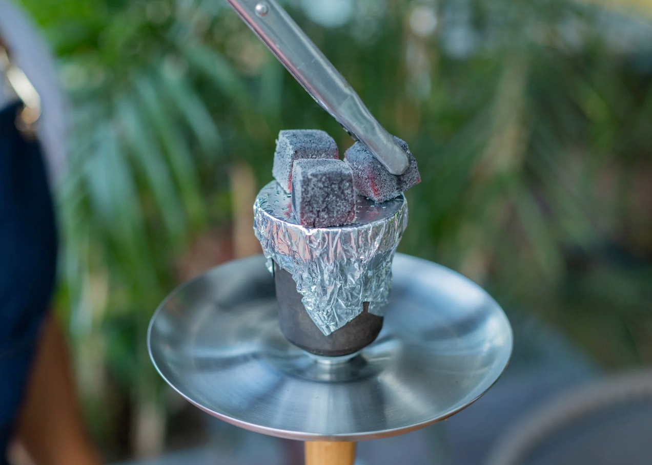 Placing coals on the hookah bowl.png__PID:1fb27983-e040-4811-8372-bf77d9e95ee1