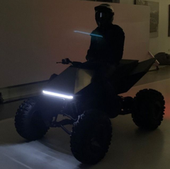 figure in blacked out clothes and black motorcycle helmet, on electric 4 wheeler quad bike in an empty warehouse