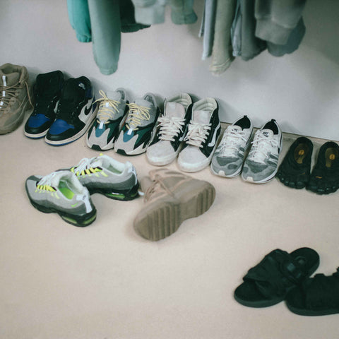 Various streetwear shoes, basketball shoes laid on floor underneath hanging clothes with retro filter
