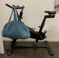 suede blue holdall bag hanging on arm of treadmill in empty room