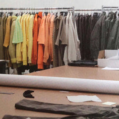 colourful rainbow clothes hanging on rails in background that lead into neutral earth tones, desk with clutter on