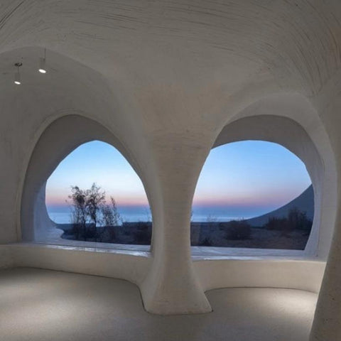 curved Hollow walls with lighting by seaside, window space in walls looks to sunset view