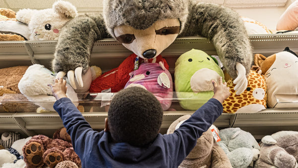 A young child reaching for a large stuffed animal