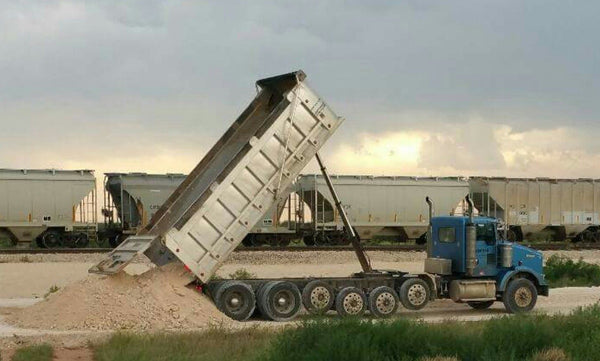 Dump truck dumping gravel into trench for backfilling