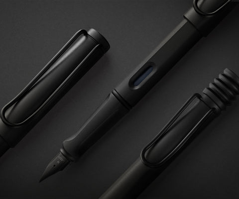 LAMY safari 2018 Special Edition All Black, with the completely-black fountain, rollerball and ballpoint pens laid out on a black surface