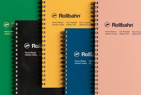 Spiral Rollbahn notebooks with green, black, yellow, blue and baby pink covers laid overlapping on each other