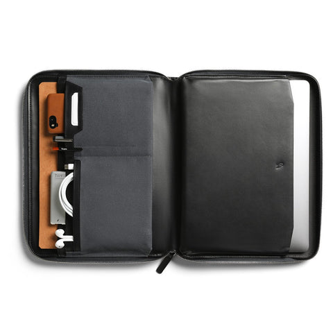 An inside view of Bellroy's Tech Folio, with a 13" laptop ensconced on the right, and lots of small accessories like phones and cables stashed neatly in the many pockets on the left
