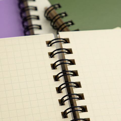 A close-up shot of a Rollbahn notebook's grid pages, which are a creamy colour with pale 5mm square grid layout bound with a black spiral binding